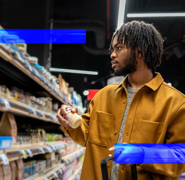 Shopper reviewing a packaged product in a retail store aisle before making a purchase.