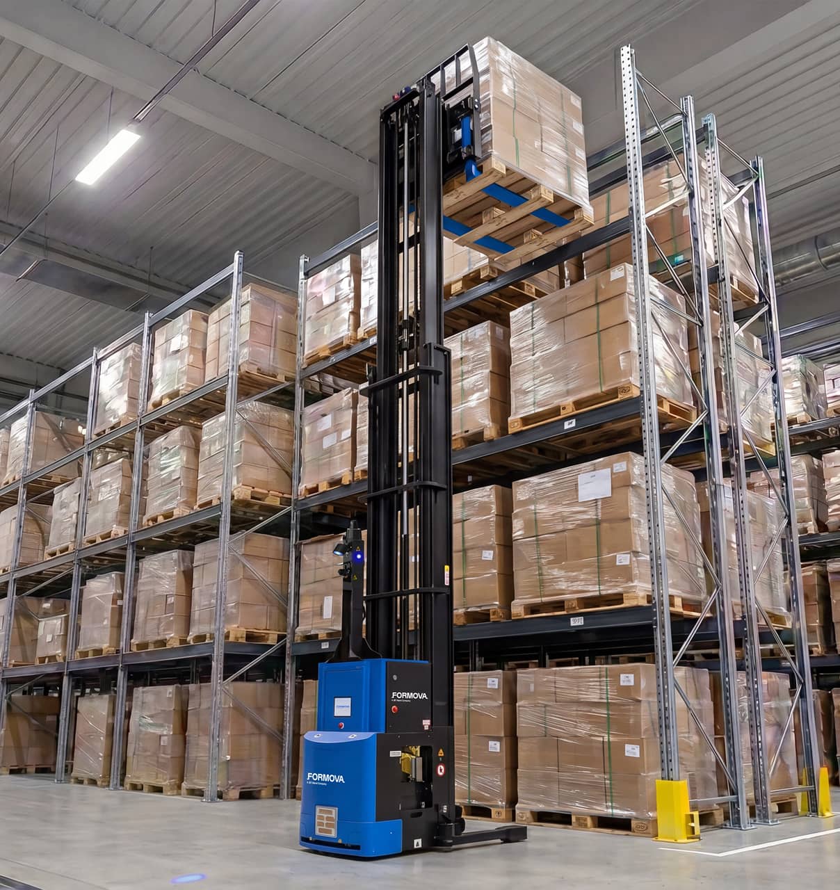 A Formova reach automated guided vehicle (agv) lifts a pallet to a high storage rack position