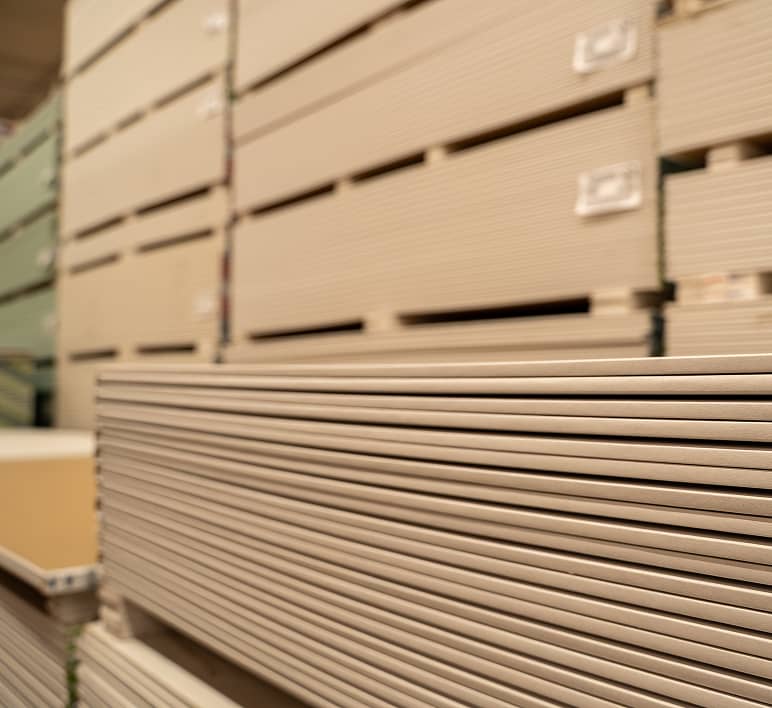 Large sheets of building materials are stored on industrial warehouse racks.