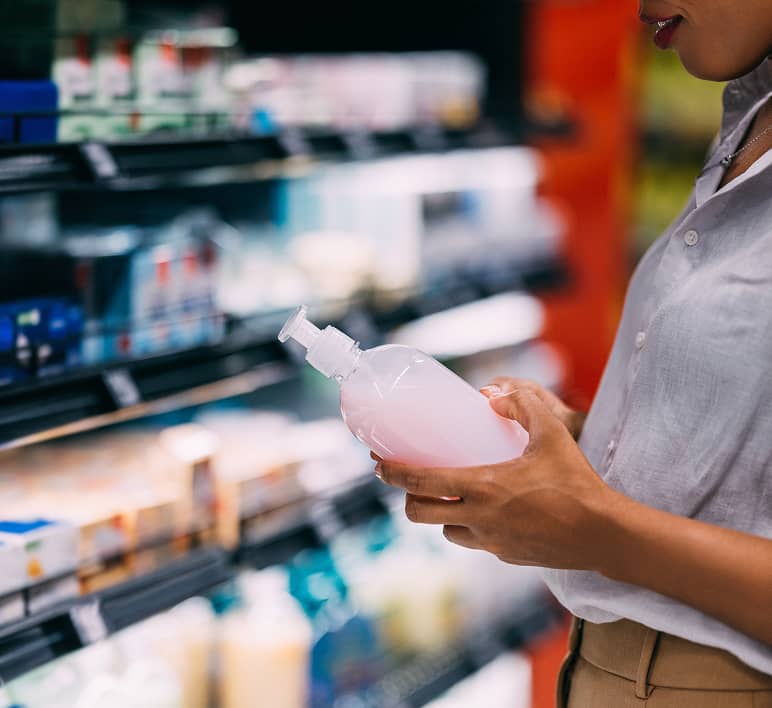 A shopper examines a consumer product on a retail shelf.