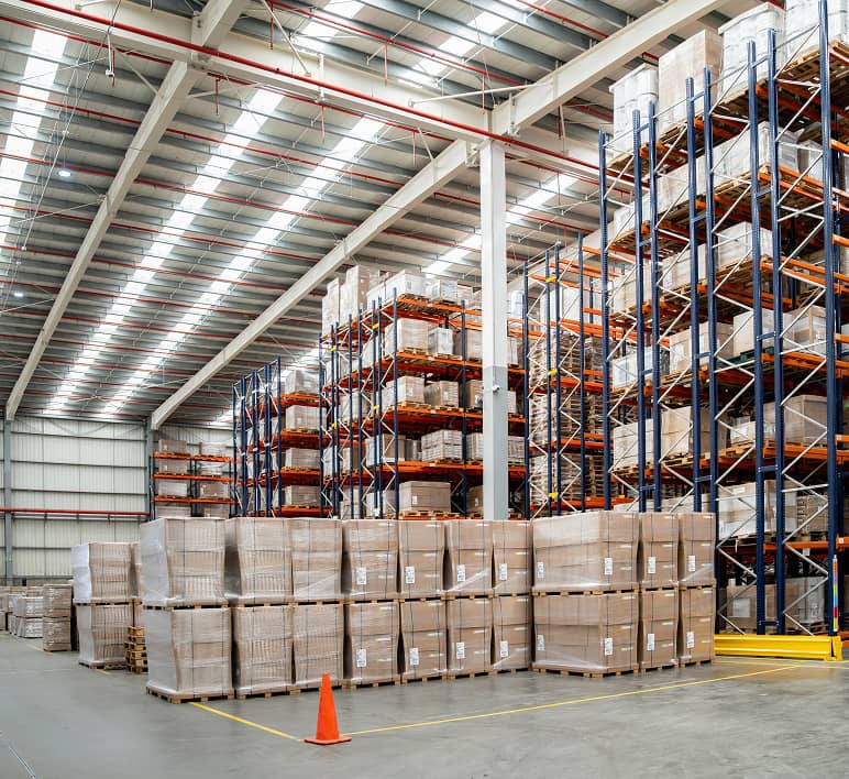Rows of pallet racks filled with inventory extend through a warehouse.