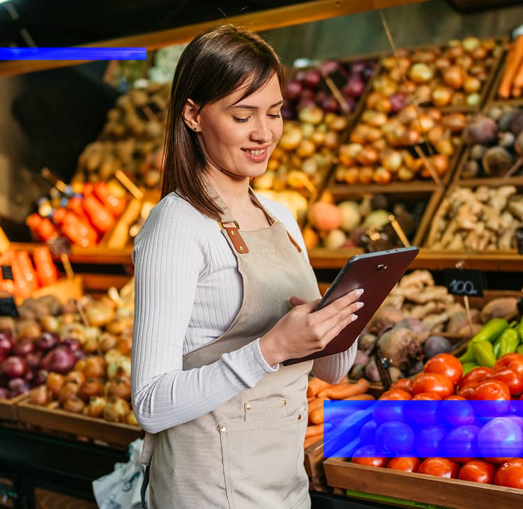 Retail employee using a tablet in a grocery produce department to support inventory.