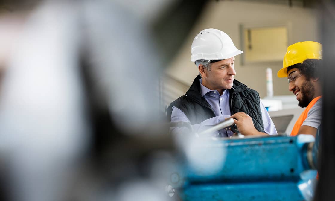 Two professionals discuss operations on a manufacturing floor.
