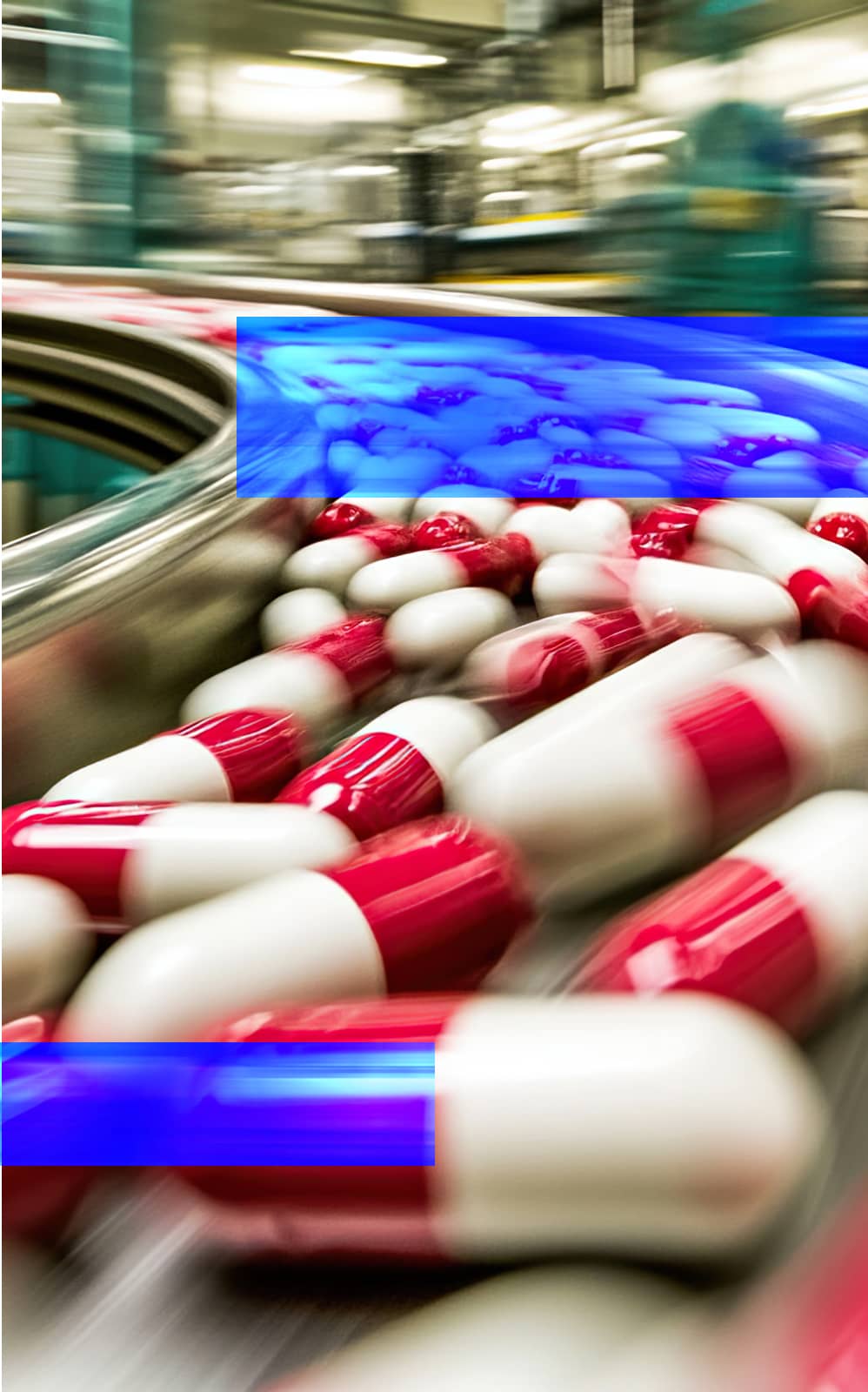 Pharmaceutical capsules traveling along an automated manufacturing conveyor.