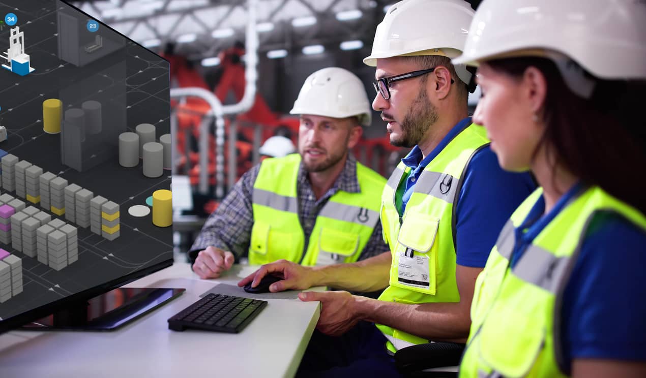 A team of industrial engineers and operations specialists review an automated warehouse on a large monitor