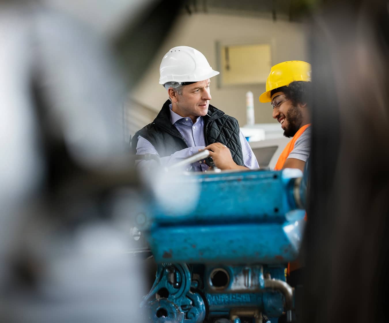 Two industrial professionals wearing safety gear collaborate on the production floor
