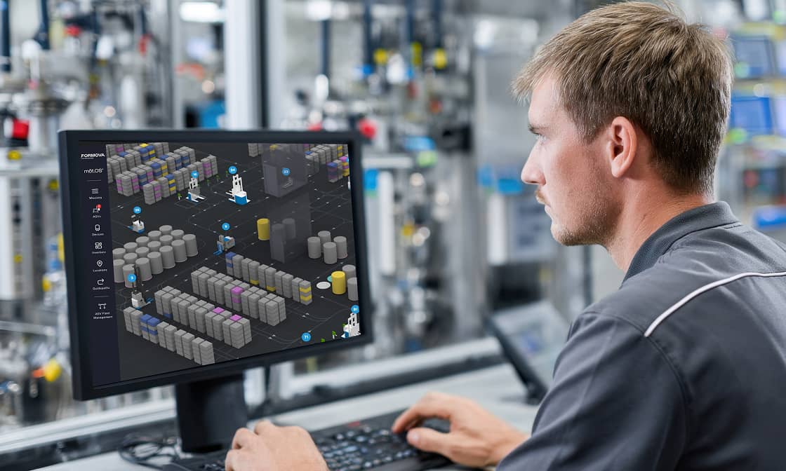 An employee reviews a warehouse management dashboard on a computer monitor.