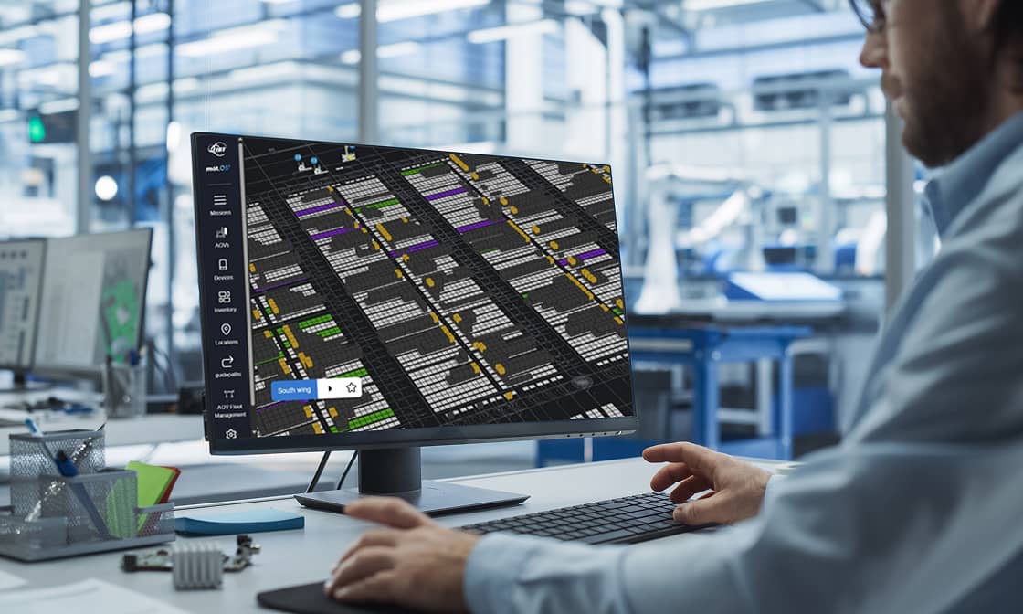 An employee reviews a warehouse management dashboard on a computer monitor.