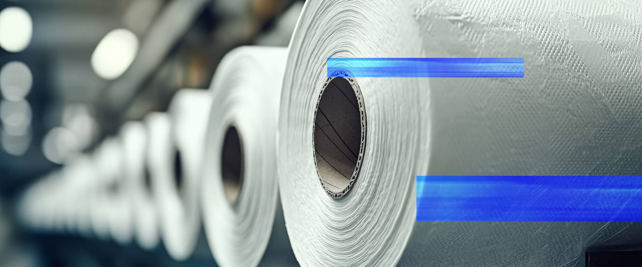 Large rolls of tissue paper in a production facility, representing automation solutions for packaging companies