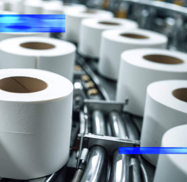 Large rolls of tissue paper are staged in a production facility, representing automation solutions for packaging companies